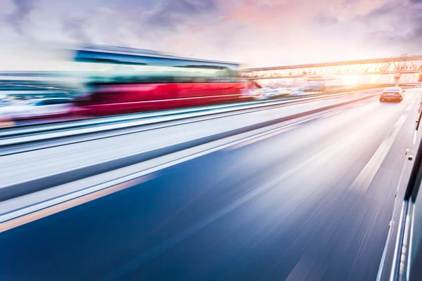 Carro dirigindo na auto-estrada ao pôr do sol, borrão de movimento — Fotografia de Stock