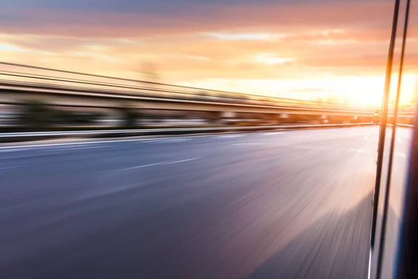 Carro dirigindo na auto-estrada ao pôr do sol, borrão de movimento — Fotografia de Stock