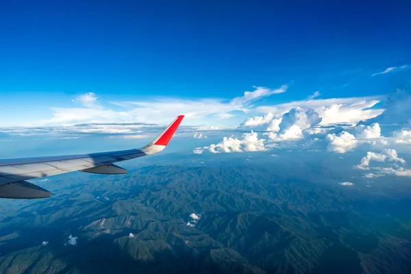 Nubes y cielo visto a través de la ventana de un avión — Foto de Stock