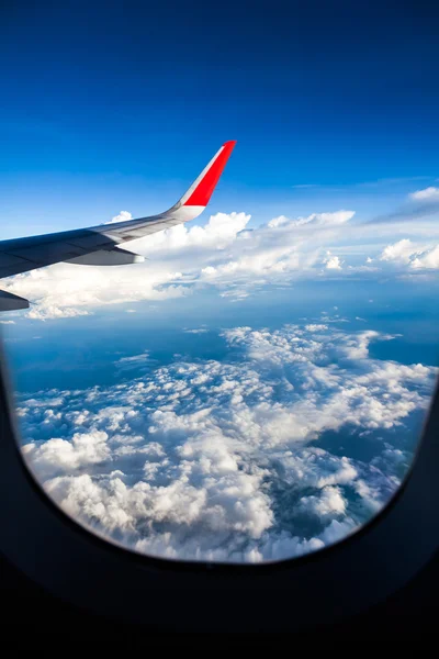 Nubes y cielo visto a través de la ventana de un avión — Foto de Stock