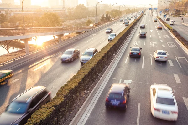 Coches en movimiento borroso en la calle durante la puesta del sol — Foto de Stock