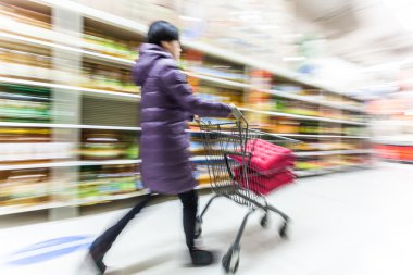 Genç bir kadın süpermarkette alışveriş yapıyor.