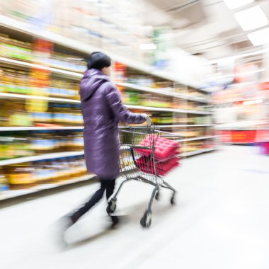Genç bir kadın süpermarkette alışveriş yapıyor.
