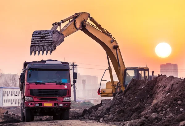 Günbatımında çalışan ağır tekerlekli ekskavatör makine — Stok fotoğraf