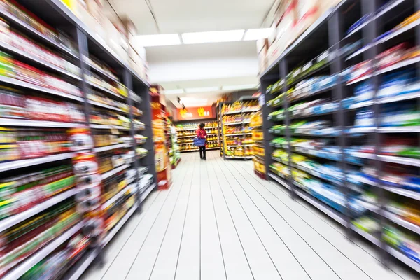 Jovem mulher fazendo compras no supermercado, borrão de movimento — Fotografia de Stock