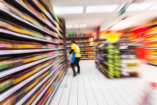 Jonge vrouw winkelen in de supermarkt, bewegingsonscherpte — Stockfoto