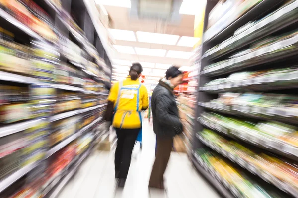 Jovem mulher fazendo compras no supermercado, borrão de movimento — Fotografia de Stock