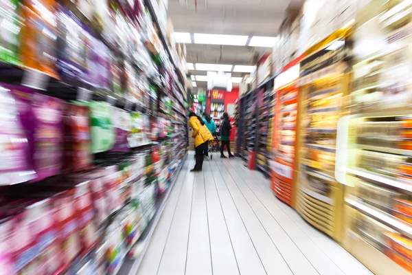 Mujer joven de compras en el supermercado, desenfoque de movimiento — Foto de Stock