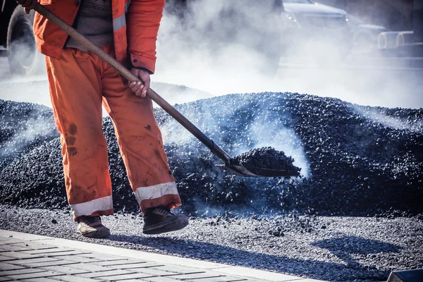 Lavoratori che producono asfalto con pale a constructio strada — Foto Stock