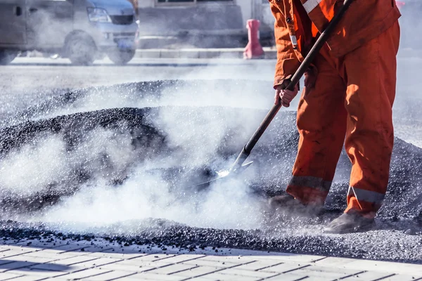 Lavoratori che producono asfalto con pale a constructio strada — Foto Stock