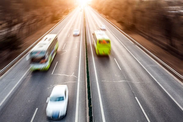 車の動きは日没時に路上ぼかし — ストック写真