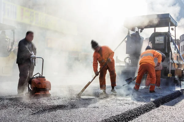 Workers making asphalt with shovels at road constructio — Stock Photo, Image