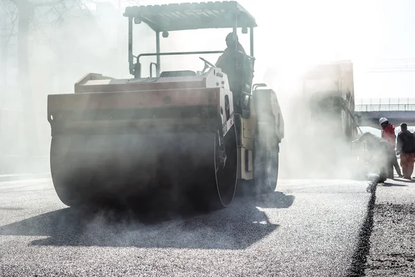 Lavoratori che producono asfalto con pale a constructio strada — Foto Stock