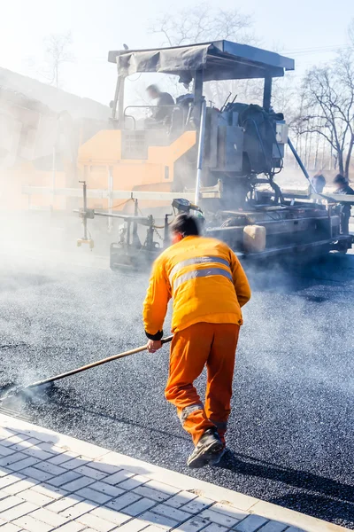 道路建設でシャベルでアスファルトを作る労働者 — ストック写真