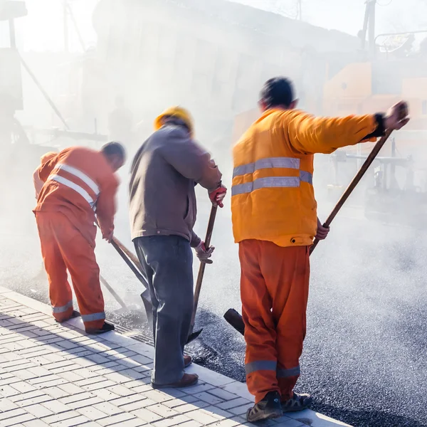 Workers making asphalt with shovels at road constructio — Stock Photo, Image