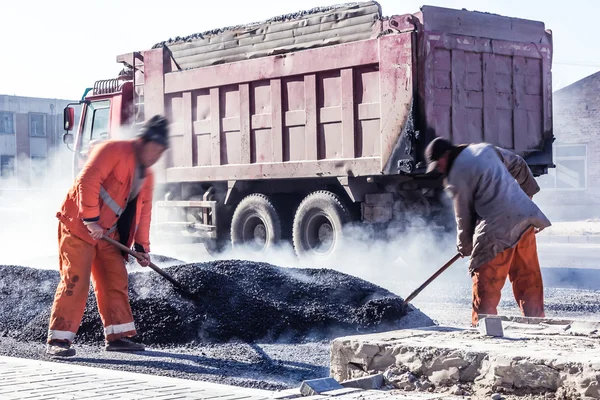 Рабочие, делающие асфальт с лопатами на дорожном строительстве — стоковое фото