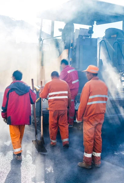 Робітники роблять асфальт з лопатями при будівництві доріг — стокове фото