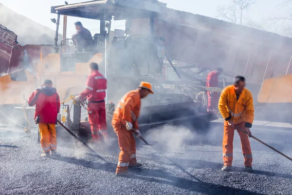 道路建設でシャベルでアスファルトを作る労働者 — ストック写真