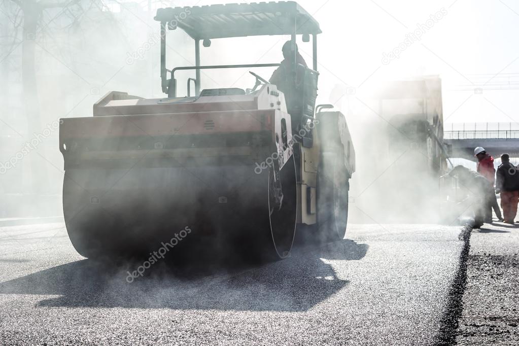 Workers making asphalt with shovels at road constructio