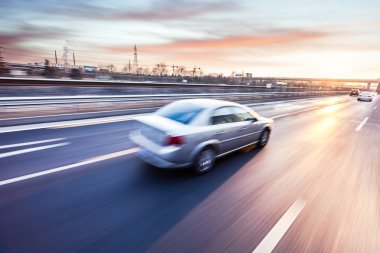 Car driving on freeway at sunset, motion blur  clipart
