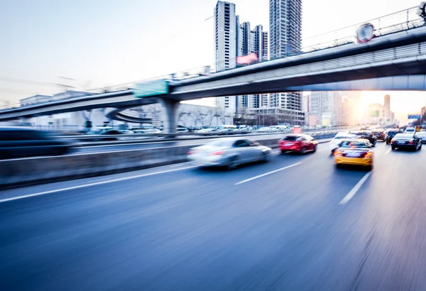 Bilkörning på motorväg vid solnedgången, rörelse suddig — Stockfoto