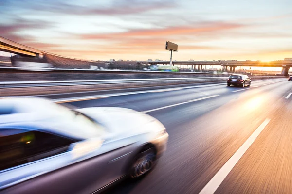 Mașină de conducere pe autostradă la apus de soare, blur mișcare — Fotografie, imagine de stoc