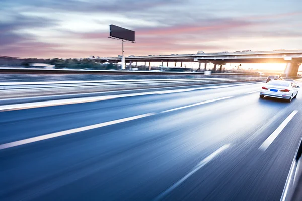Auto fährt bei Sonnenuntergang auf Autobahn, Bewegungsunschärfe — Stockfoto