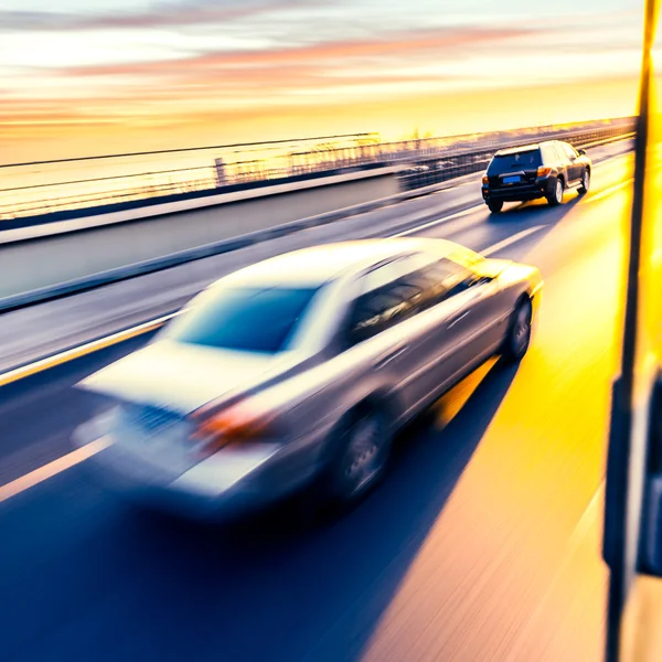 Coche conduciendo en la autopista al atardecer, desenfoque de movimiento — Foto de Stock