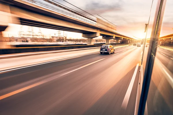 Auto rijden op de snelweg bij zonsondergang, bewegingsvervaging — Stockfoto