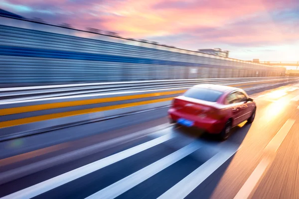 Voiture conduisant sur l'autoroute au coucher du soleil, flou de mouvement Photo De Stock