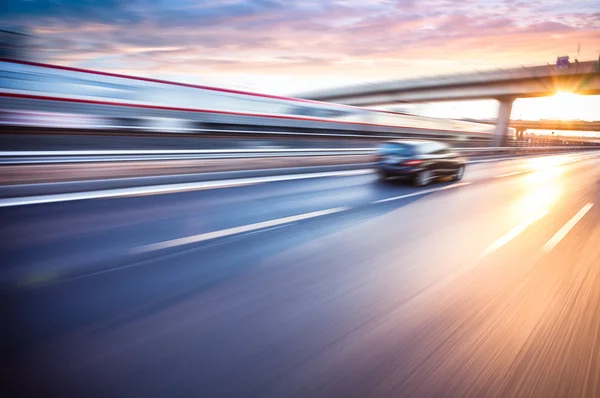 Voiture conduisant sur l'autoroute au coucher du soleil, flou de mouvement Photos De Stock Libres De Droits