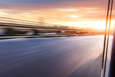 Car driving on freeway at sunset, motion blur clipart