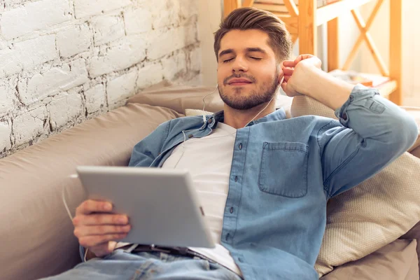 Jovem com gadget em casa — Fotografia de Stock