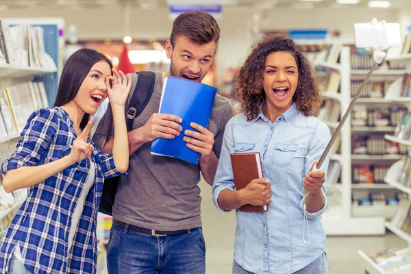 Studenti con gadget in libreria — Foto Stock