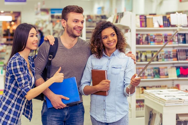 Studenti con gadget in libreria — Foto Stock