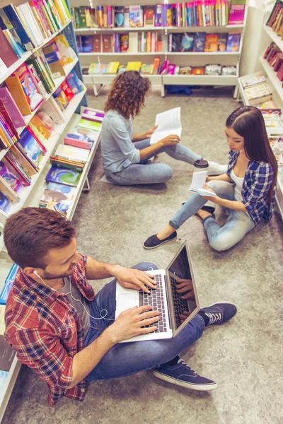 Estudantes com gadget na livraria — Fotografia de Stock