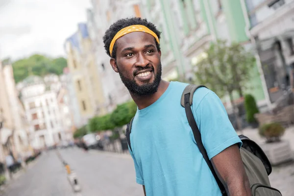 若い黒人の男がバックパックを持って橋の通りを歩いている間に笑う — ストック写真