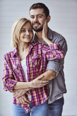 Genç, neşeli ve sevgi dolu bir çiftin portresi. Kameraya bakıp birbirlerine sarılıyorlar.
