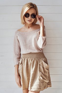 Güneş gözlüklü ve evde kameraya gülümseyen güzel bir kızın portresi.