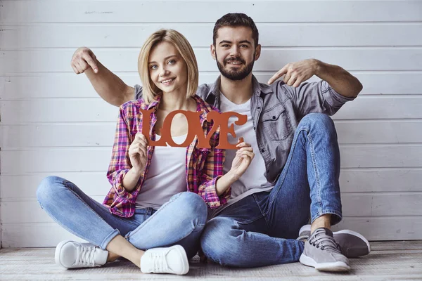 Jovem Feliz Casal Amoroso Sentado Chão Segurando Sinal Amor Sorrindo — Fotografia de Stock