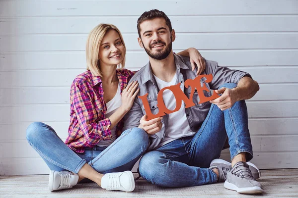 Jovem Feliz Casal Amoroso Sentado Chão Segurando Sinal Amor Sorrindo — Fotografia de Stock