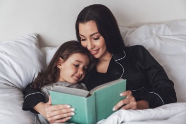 İyi geceler. Genç ve güzel bir anne küçük kızını yatağa yatırır ve geceleri ona çocuk hikayeleri kitabı okur..