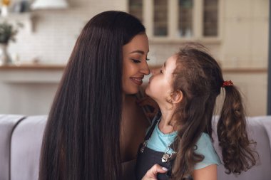 Mutlu genç anne ve küçük kızı birlikte vakit geçirir ve evdeki oturma odasındaki kanepede oturarak eğlenirler..