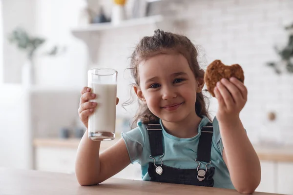 Szczęśliwa Dziewczynka Uśmiecha Się Szczęśliwie Gdy Pije Pyszne Mleko Ciasteczka — Zdjęcie stockowe