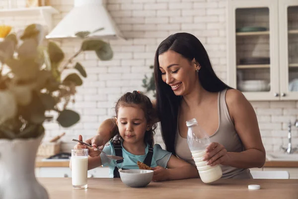 Młoda Szczęśliwa Matka Przygotowuje Śniadanie Dla Swojej Córeczki Dodając Mleko — Zdjęcie stockowe