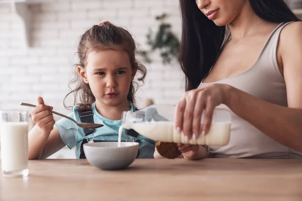 Młoda Szczęśliwa Matka Przygotowuje Śniadanie Dla Swojej Córeczki Dodając Mleko — Zdjęcie stockowe