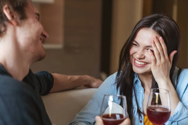 一对快乐的年轻夫妇坐在家里的沙发上 举着酒杯 面带微笑地望着对方 — 图库照片