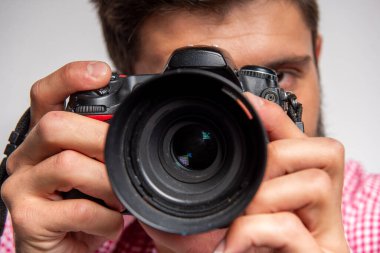 Kameranın objektifine odaklanmış, objektifin arkasına odaklanmış, nötr arka planda izole edilmiş, hassasiyeti, profesyonel fotoğrafçılığı, odaklanmayı ve görsel hikaye anlatımını temsil eden makro görüş..