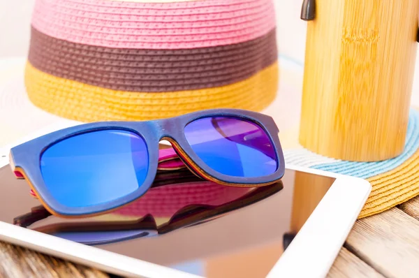 Wooden colorful sunglasses, tablet and hat — Stock Photo, Image