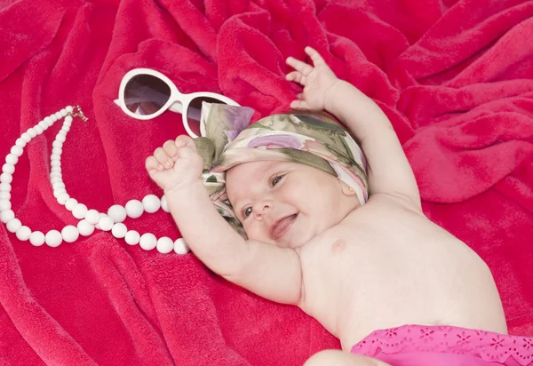 Little smiley baby girl on red blanket — Stock Photo, Image